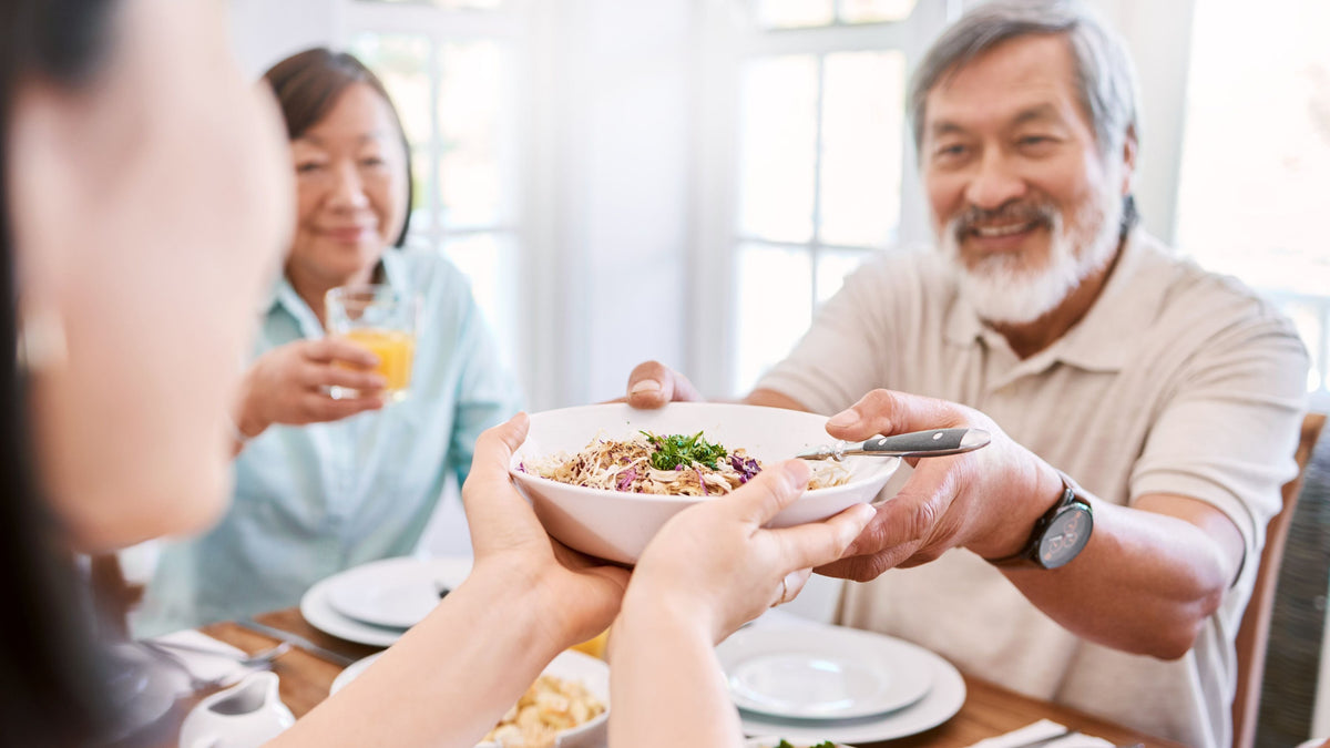 Gemeinsames Mittagessen: Familie teilt eine gesunde Mahlzeit, die der Longevity Ernährung förderlich ist.