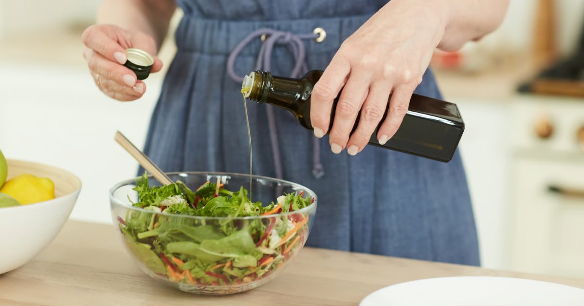 Olivenöl wird über einen frischen Salat gegeben – Olivenöl Dosierung im Alltag