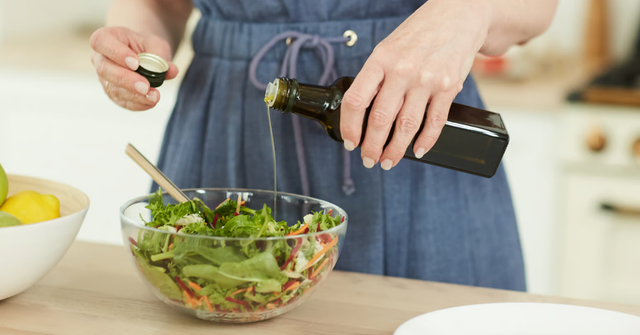 Olivenöl wird über einen frischen Salat gegeben – Olivenöl Dosierung im Alltag