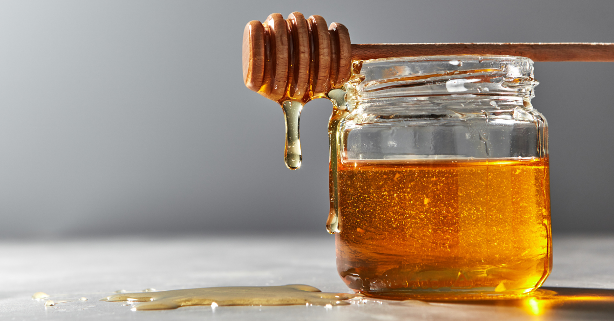 Flüssiger Honig im Glas mit Honiglöffel – Honig Dosierung und Verzehrmenge