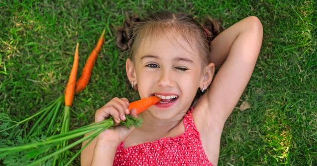 Kind isst eine frische Karotte – Vitamin A Dosierung und Versorgung im Alltag